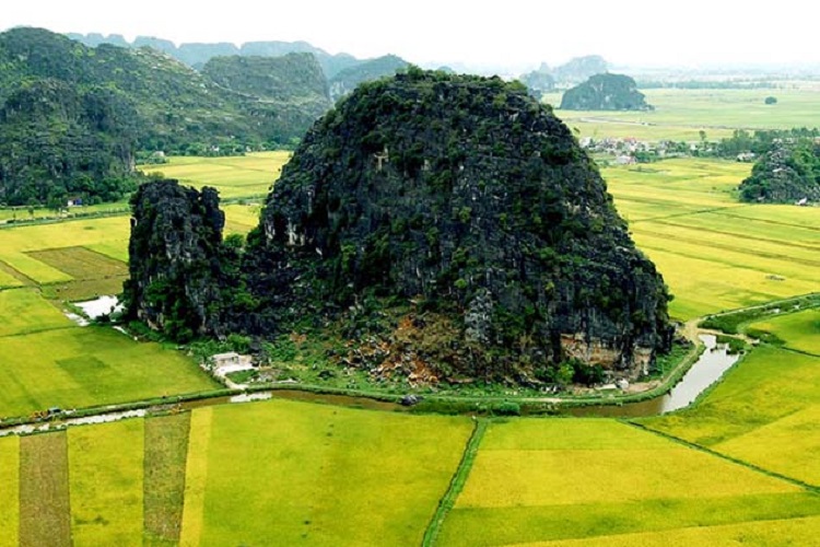 A karst tower stands isolated on the fields